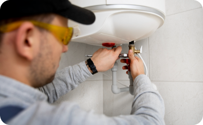 Fachmann montiert einen Warmwasserspeicher und schließt die Wasserleitungen an